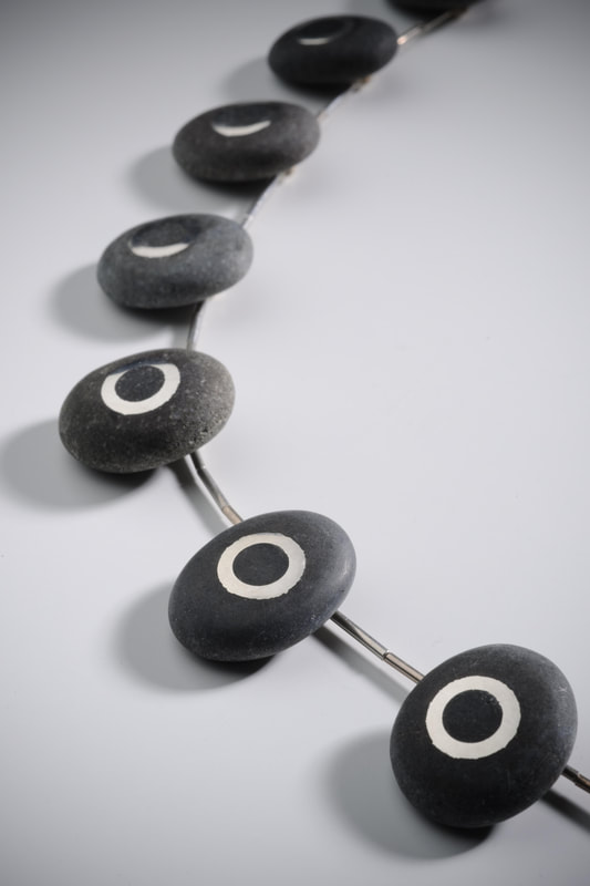 The necklace is made from Greywacke pebbles from the Bank Peninsular in the South Island of New Zealand. Sterling silver circles are cast directly into the pebble. 